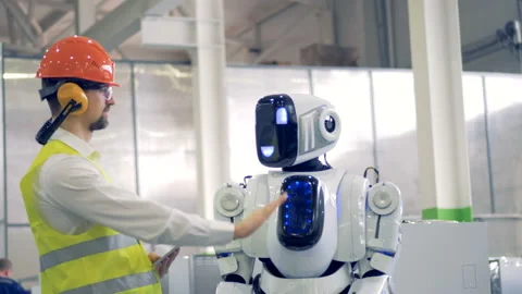 Human factory worker and an android give each other a hi-five at a factory Stock Footage 88875199