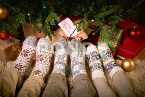 Human feet in woolen socks by xmas tree Stock Photos
