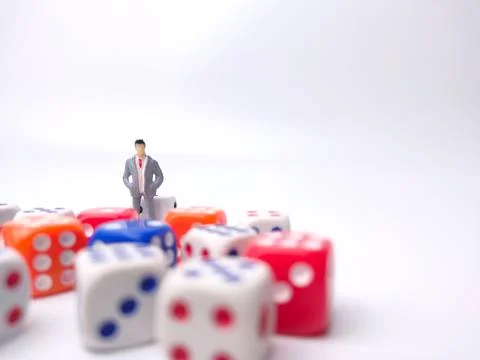 Human figurine is surrounded by a vibrant array of colorful dice Stock Photos