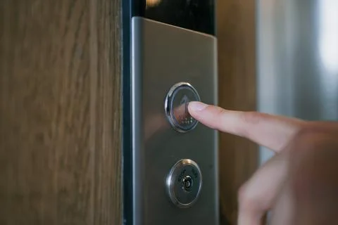 Human finger pressing the up arrow button on a metallic elevator control panel Stock Photos