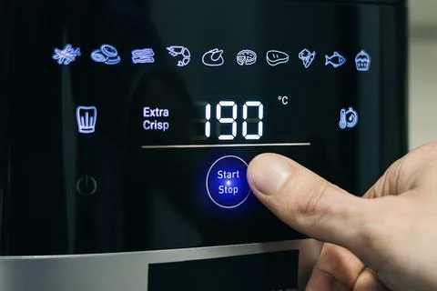 Human finger pressing start button on digital air fryer panel. Digital air .. 写真素材