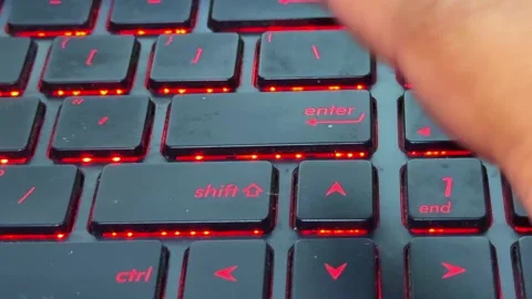 Human finger typing on a backlit laptop keyboard in "enter" button, r Stock Footage 332962054