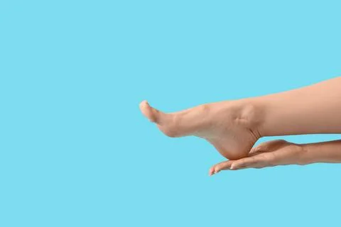Human foot supported by hand on blue background Stock Photos