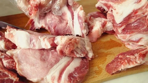 A human with gloves cuts the meat in layers. A juicy, fatty piece of meat is cut Video stock 144703097