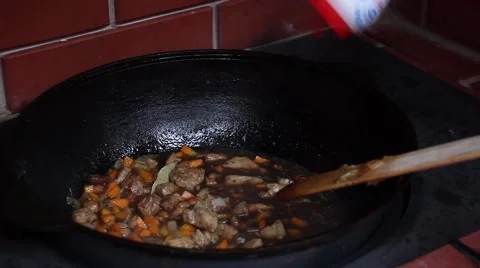 Human hand added salt  in the boiling oil with meat and vegetables Video stock 56315746
