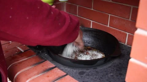 Human hand added white rice in the boiling oil with meat and mixing it Stockbeeldmateriaal 56315899