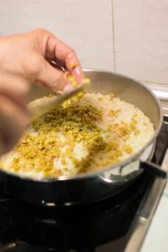 Human hand adding chopped green olives to rice Stock Photos