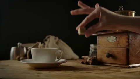 Human hand adds cane brown sugar cube into rotating towards white cup of coffee Stock Footage 136814389