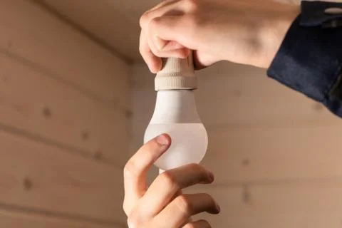 Human hand changing a light bulb. Replacing the light bulb at home Stock Photos