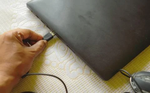 Human hand connecting Computer mouse connection cable plug-in the laptop keyb Stock Photos