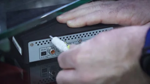 Human hand connects audio cable to TV set-top box Video stock 281553987