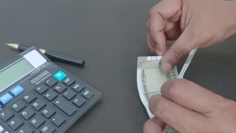 Human hand counting new 500 rupee indian currency note against a calculator a Stock Footage 166804894