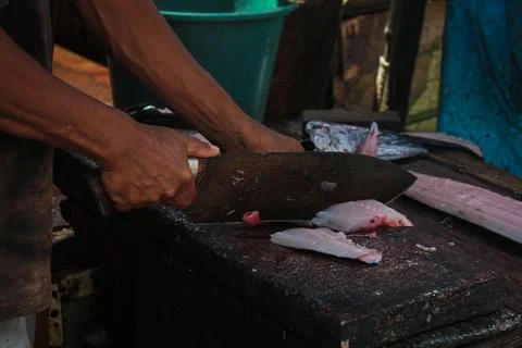 Human hand cutting fish using machete Stock Photos