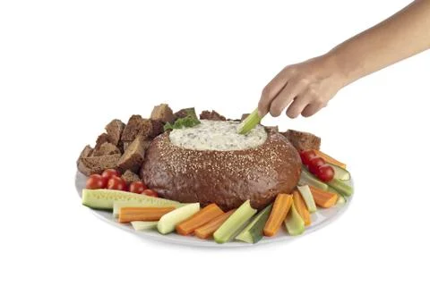 Human hand dipping a slice of vegetable on spinach dip Stock Photos