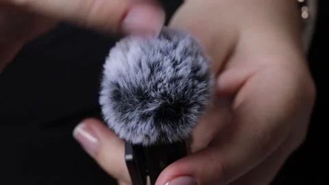 Human hand gently moving a finger across the furry wind protection of a mic.. Stock Footage 320736466