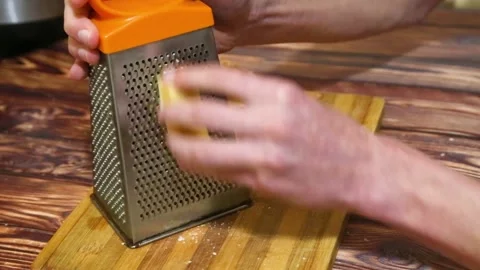 Human hand grating cheese on kitchen table. Homemade cooking Stock Footage 225150048
