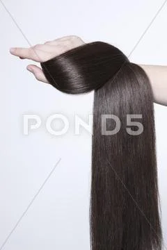 Human Hand Holding Brown Hair Against White Background, Close Up