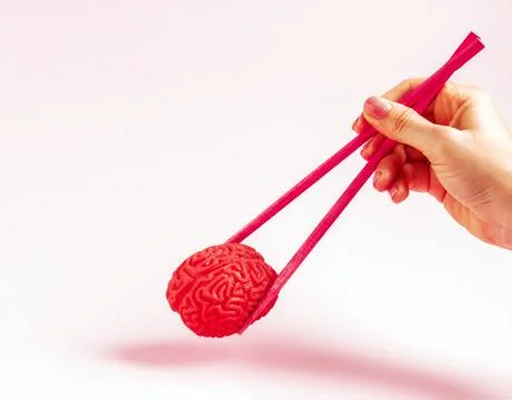 Human hand holding human brain with two chopsticks. Creative concept. Stock Photos