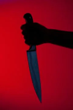 Human hand holding kitchen knife against red background Stock Photos