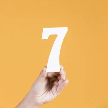Human hand holding number seven against yellow background Resolution and high Stock Photos