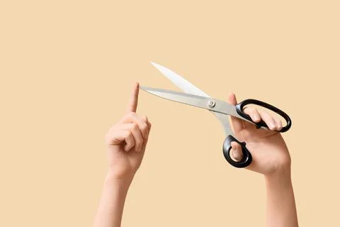 Human hand holding open scissors with another hand pointing at the sharp blad Stock Photos