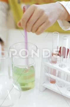 Human hand holding pipette in beaker, elevated view Stock Photos
