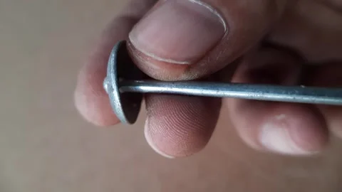 Human hand holding a silver zinc roofing nail with a wide round head and a .. Video stock 324825337