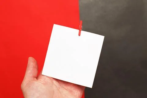Human hand holding sticker with empty mockup for text hanging on pin on red a 스톡 사진