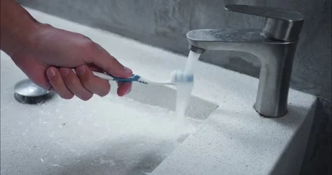 Human hand holding toothbrush under running water personal hygiene Regular Stock Footage 264743344