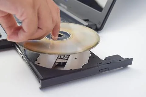 Human hand inserting compact disc into laptop optical drive, minimal photo .. 스톡 사진