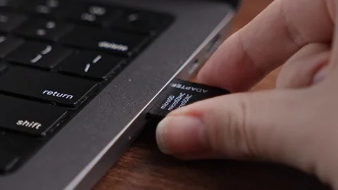 Human hand inserts a black microSD card adapter, labeled microSDHC and micr.. Stock Footage 320167239