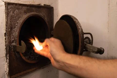 Human Hand Lighting Fire Inside Open Stove Door Foto stock