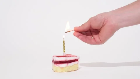 Human hand lights a candle of anniversary or birthday cake  on white background, Stock Footage 244392483