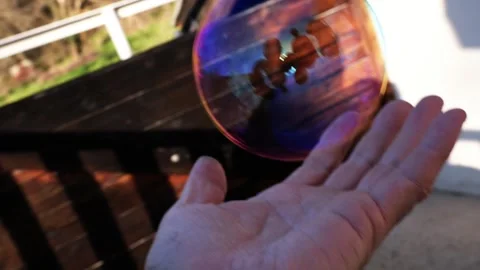 A human hand moving under a floating soap bubble Stockbeeldmateriaal 330362020