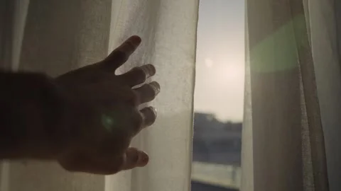 Human hand opening a window curtain at sunrise Stock Footage 339886016