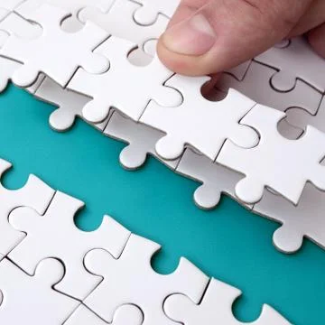 The human hand paves the way to the surface of the jigsaw puzzle, forming a b 写真素材