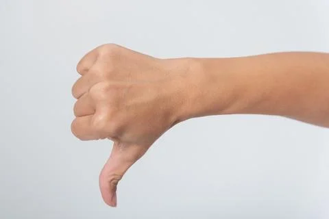 Human hand performing a thumbs down gesture against a neutral background, e.. Stock Photos
