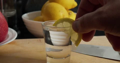 Human hand placing a slice of lemon on rim of glass full of water Stock Footage 170855576