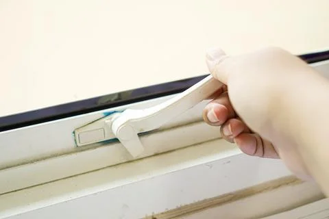 Human hand on plastic window lock handle. Stock Photos