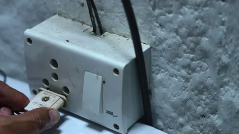 Human hand plugging a device into a dirty old power socket and turning Stock Footage 345188776
