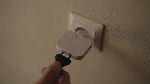 Human hand plugging white multi socket power adapter into wall outlet and Video stock 342769767