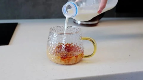 Human hand pours milk into cup of black tea simple process of making classic tea Video stock 291237308