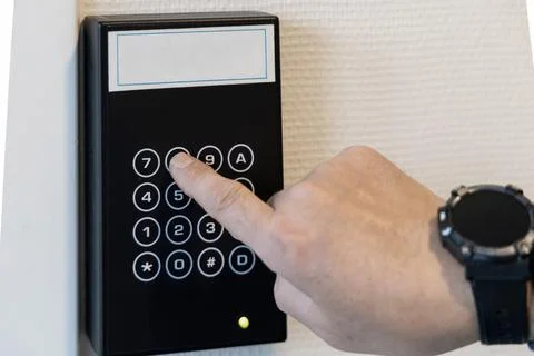 A human hand presses buttons with numbers to enter a code to open the door. Stock Photos
