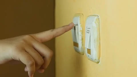 A human hand pressing a light switch on a yellow wall Stock Footage 319921701