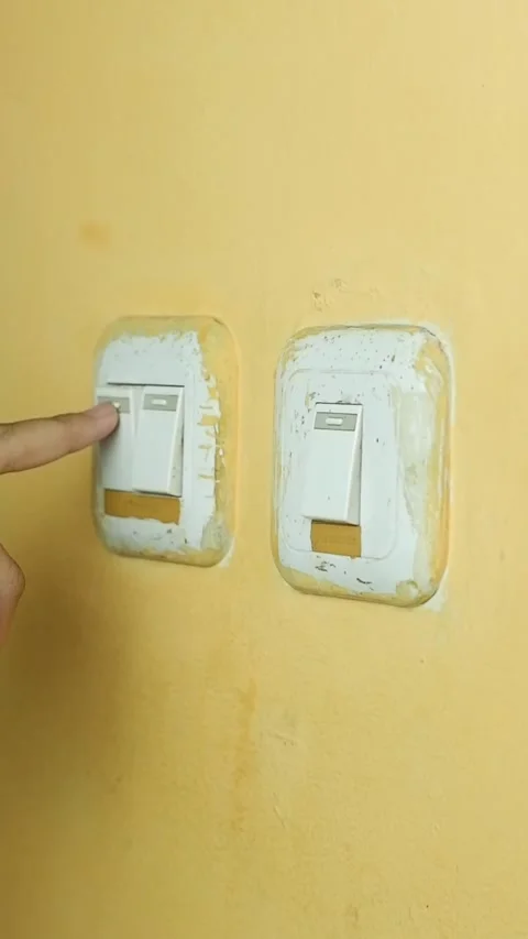 A human hand pressing a light switch on a yellow wall Stock Footage 319921702