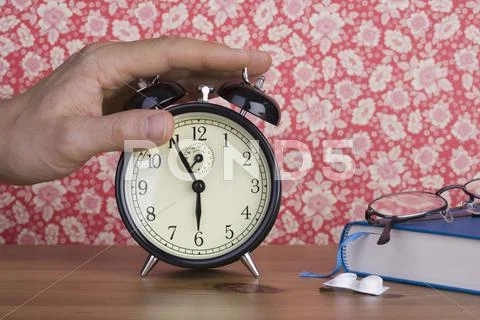 A Human Hand Pressing An Old-Fashioned Alarm Clock