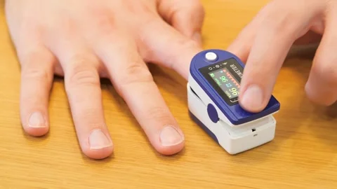 Human hand pulse oximeter used to measure pulse rate and oxygen levels close up Video stock 269833998