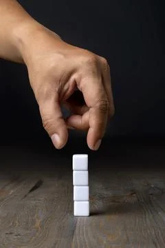 A human hand put a stack of small cubes 写真素材