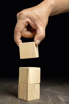 A human hand put a stack of wooden cubes Stock Photos