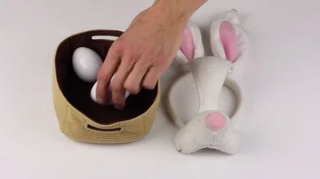 Human hand puts the attributes of Easter - basket, eggs, bunny mask Stockbeeldmateriaal 85509349